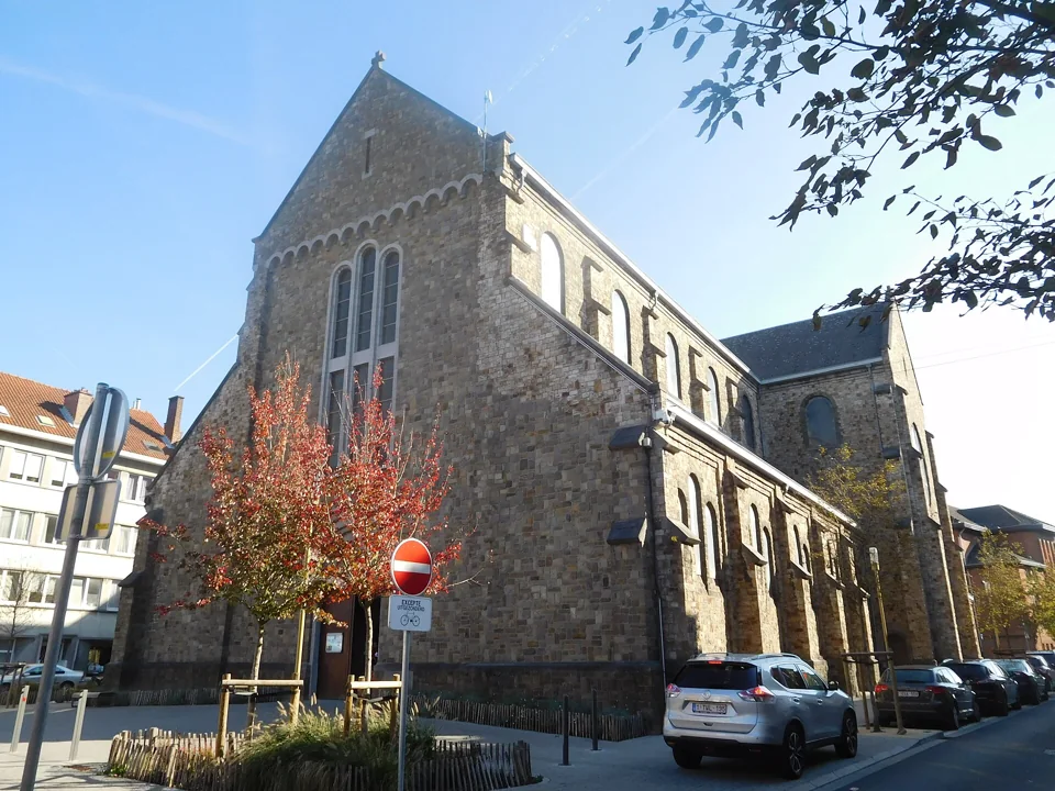 Église Sainte-Agathe en pierre, vue depuis la rue avec ses volumes latéraux et des arbres.