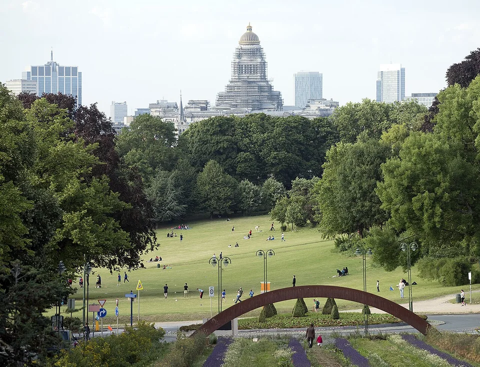 Pelouse du parc de Forest, allées et arbres, avec le Palais de Justice visible à l’arrière-plan.