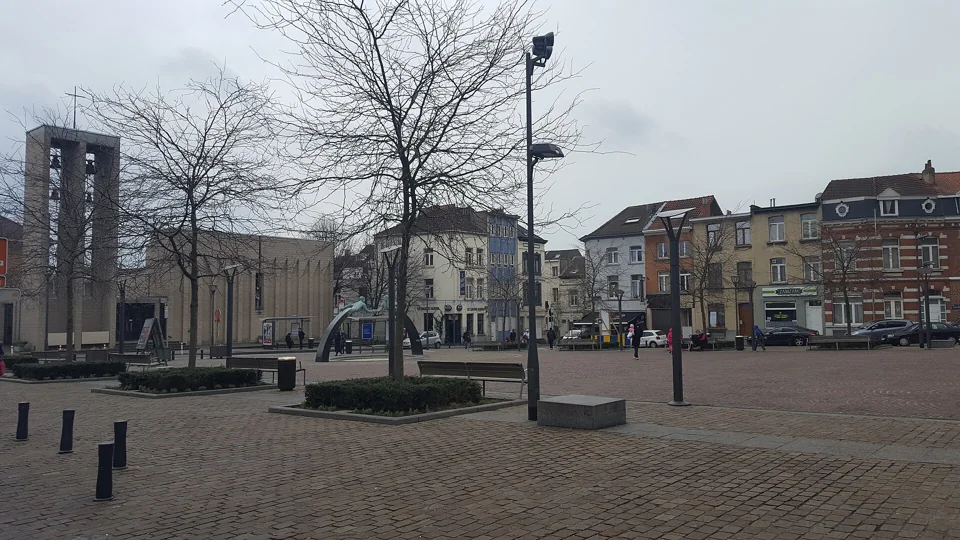 Place Henri Vanhuffel avec l’église Sainte-Anne, des arbres et les façades environnantes.