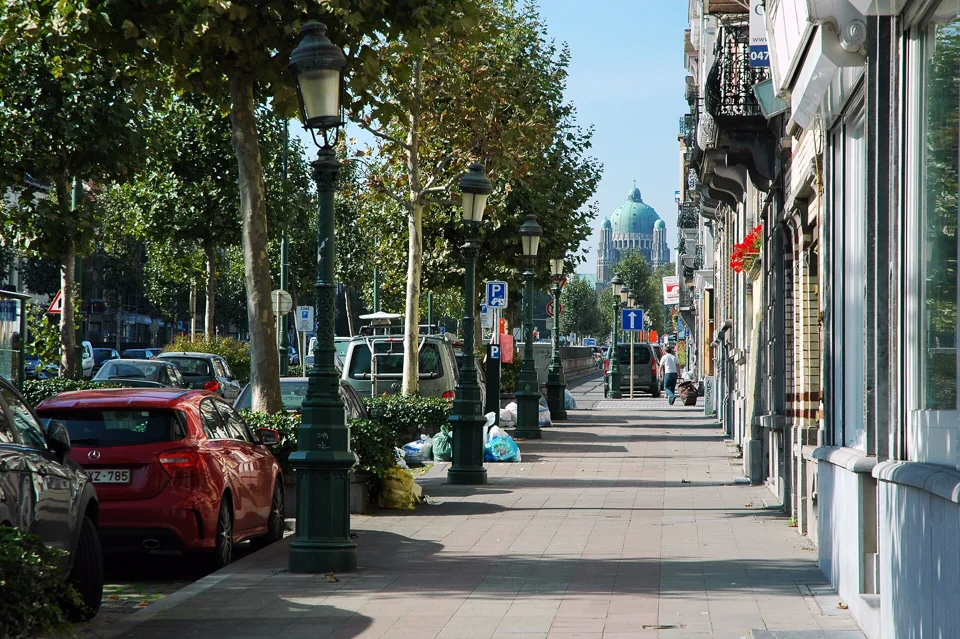 Trottoir arboré et façades du boulevard Léopold II à Molenbeek-Saint-Jean, avec la basilique visible au loin.