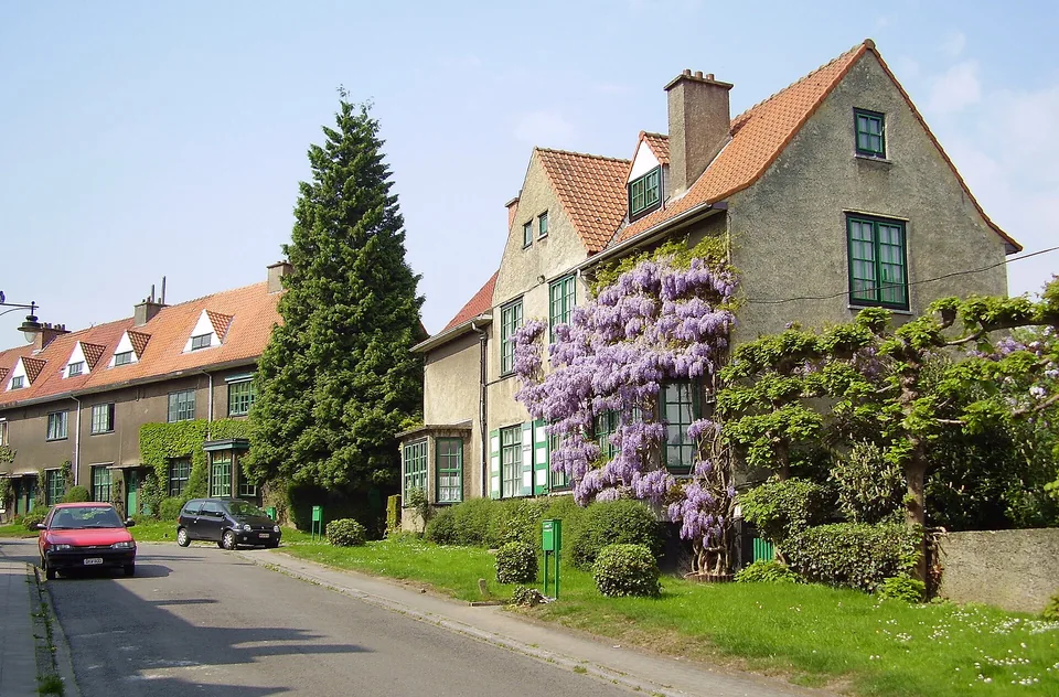 Maisons de la cité-jardin Le Logis aux toitures de tuiles et aux volets verts, le long d’une rue arborée.