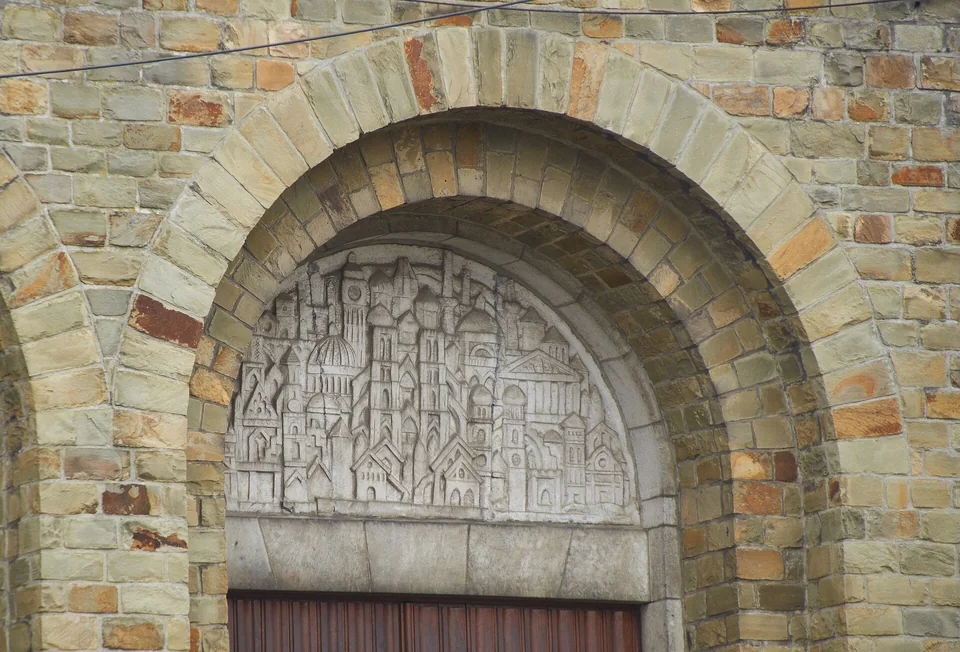 Arc en pierre et tympan sculpté du portail de l’église Notre-Dame des Grâces.
