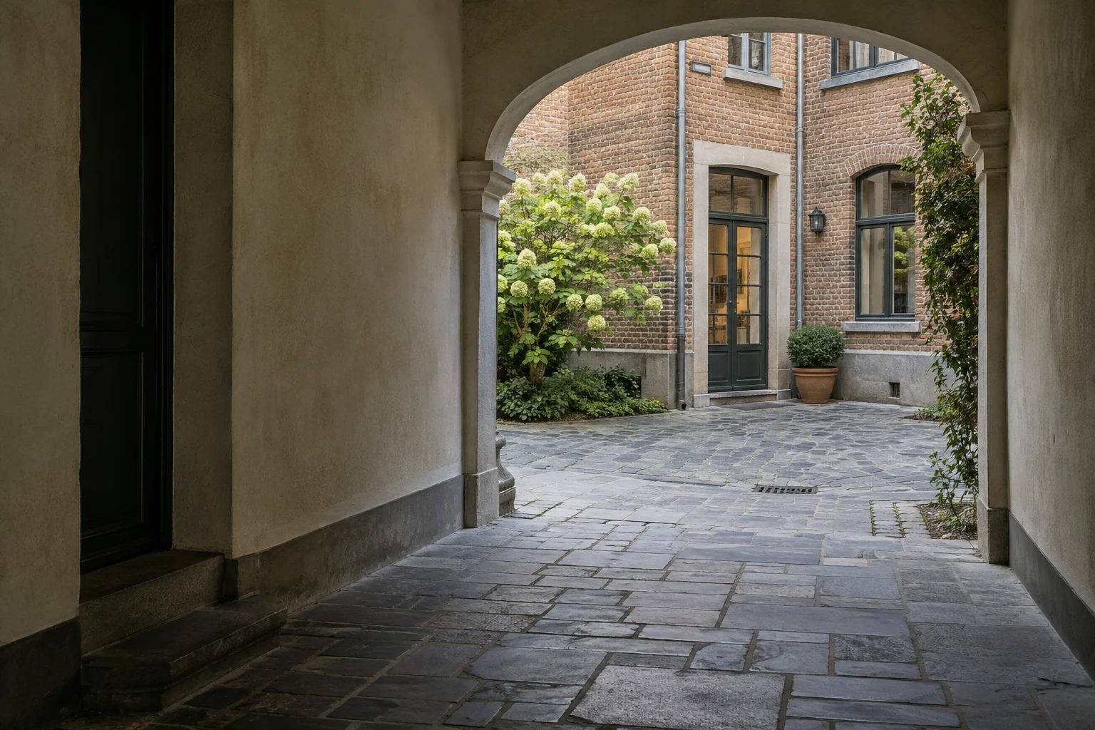 Cour intérieure en brique, vue depuis un passage voûté.