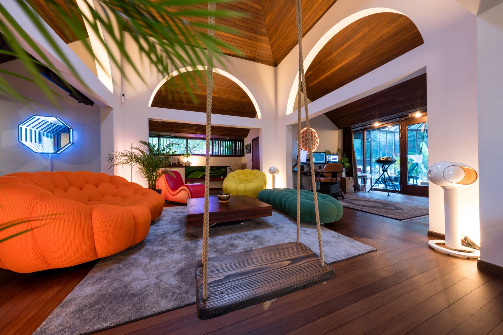 Séjour contemporain à double hauteur, plafond en bois et canapé orange.