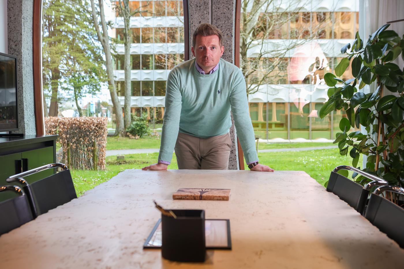 Yves Keuleers, un échange direct Yves Keuleers, debout derrière une table devant des baies vitrées.