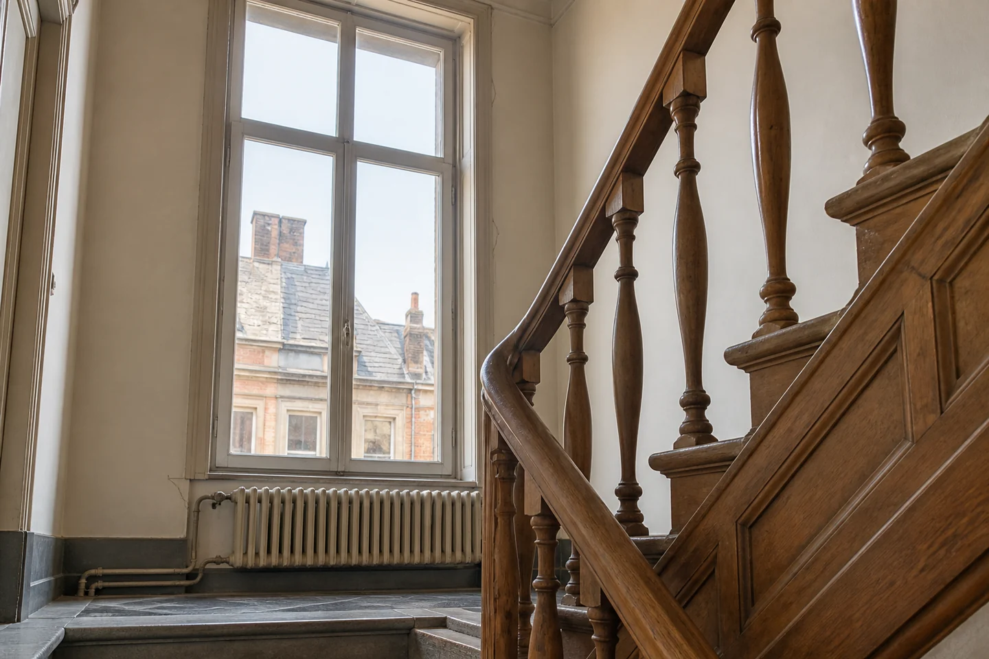 Escalier en bois et grande fenêtre dans une maison bruxelloise.